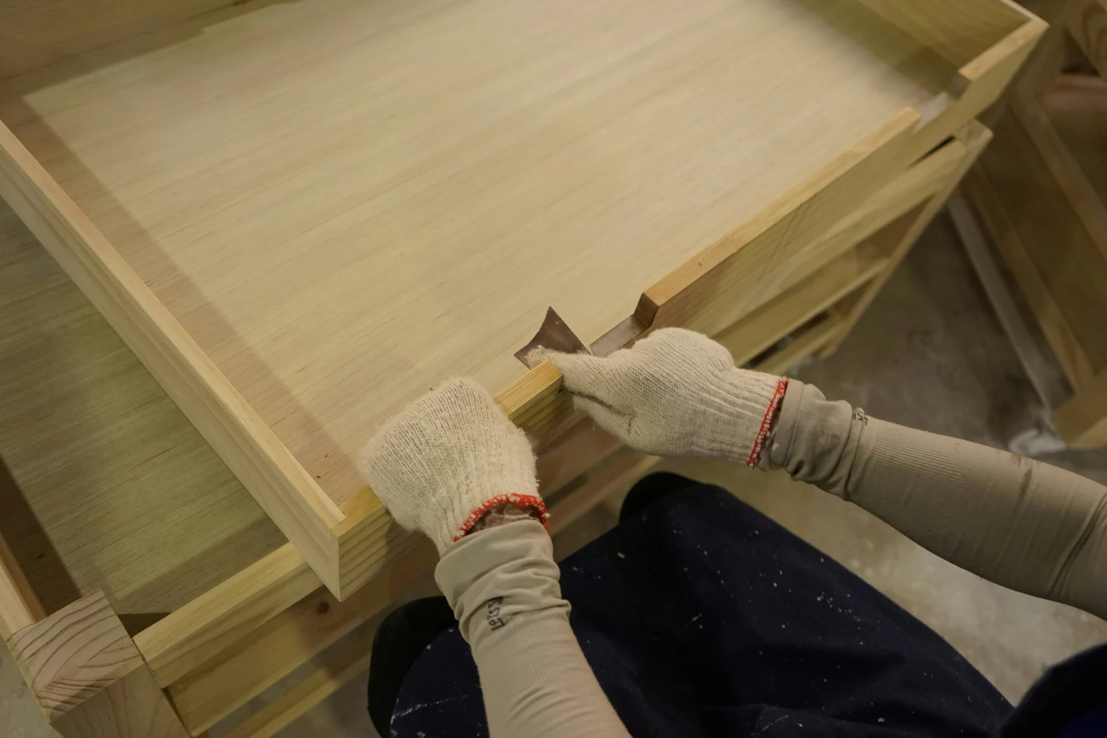 Gloved hands aligning a timber panel joint.